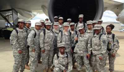 Universal Asset Management. A group of military professionals pose for a photo in front of a jumbo jet engine.