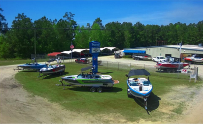 White Lake Marine, aerial view of their property with boats out on display on green grass with the building in the back of the shot.