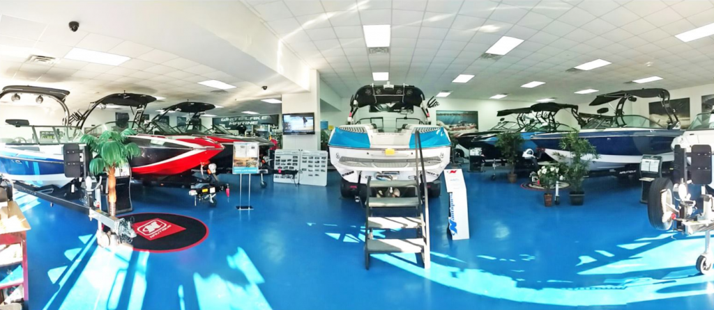 White Lake Marine, interior 180 degree view of the showroom with multiple boats in view on a blue floor.