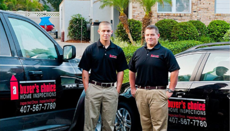 A Buyer's Choice Home Inspections employees standing in front of cars with the company logo and phone number on it.