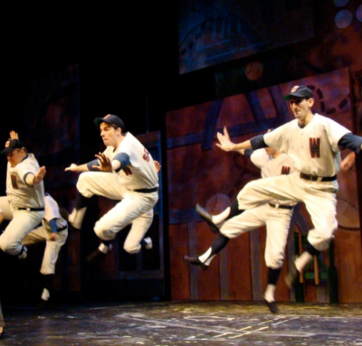 In Arlington Heights Illinois a group of men dressed in baseball uniforms jumping into the air on a stage.