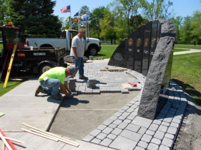 Enfield Connecticut, employees work on repaving the area around multiple plaques in granite.