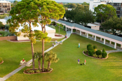 Village on the Isle, aerial view of the property showing green grass and trees and people outside.