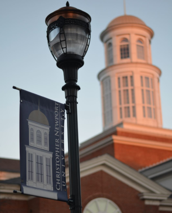 A close up on a light pole with the top of the Christopher Newport University building in the background from Newport News, Virginia.