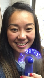 A woman holding a fan up with lit up words on it reading CLI ROCKS!. Certified Languages International