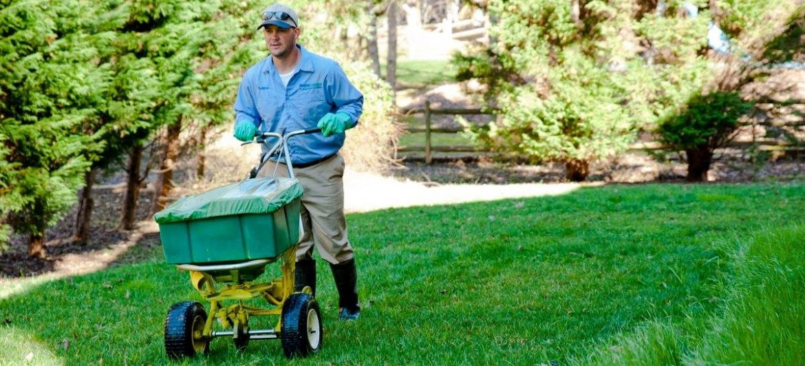 Spring-Green Lawn Care. A man using a spreader on a lawn.