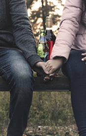 American Addiction Treatment Association. Two people sitting on a bench holding hands.