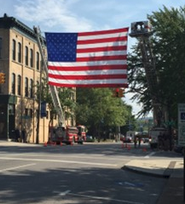 Cleveland, Tennessee. Two firetrucks lifting an american flag hanging across the city street.