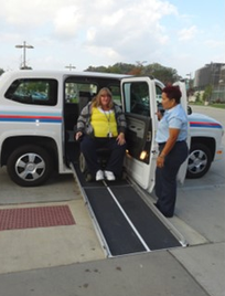 Stark Area Regional Transit Authority. A woman on a wheelchair about to go down the ramp of a vehicles with someone standing by.