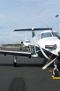 The Bartow Municipal Airport, a prop airplane sits in front of a jet on the runway with chalks on the front wheel.