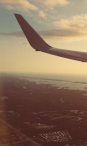 Fernandina Beach Municipal Airport. The wingtip of an airplane in flight with the ground below and sky above.