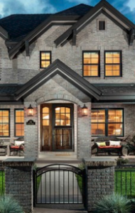 Larsen Development, front view of a home with lights on inside and a stone and metal gate out front.