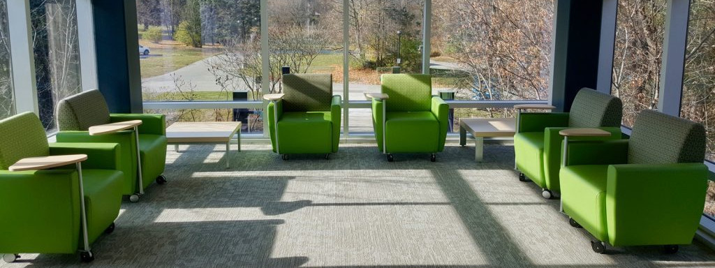 Edgewood Health Network Bellwood. A room with 3 sets of two chairs on each wall with open glass looking out to trees and greenery.