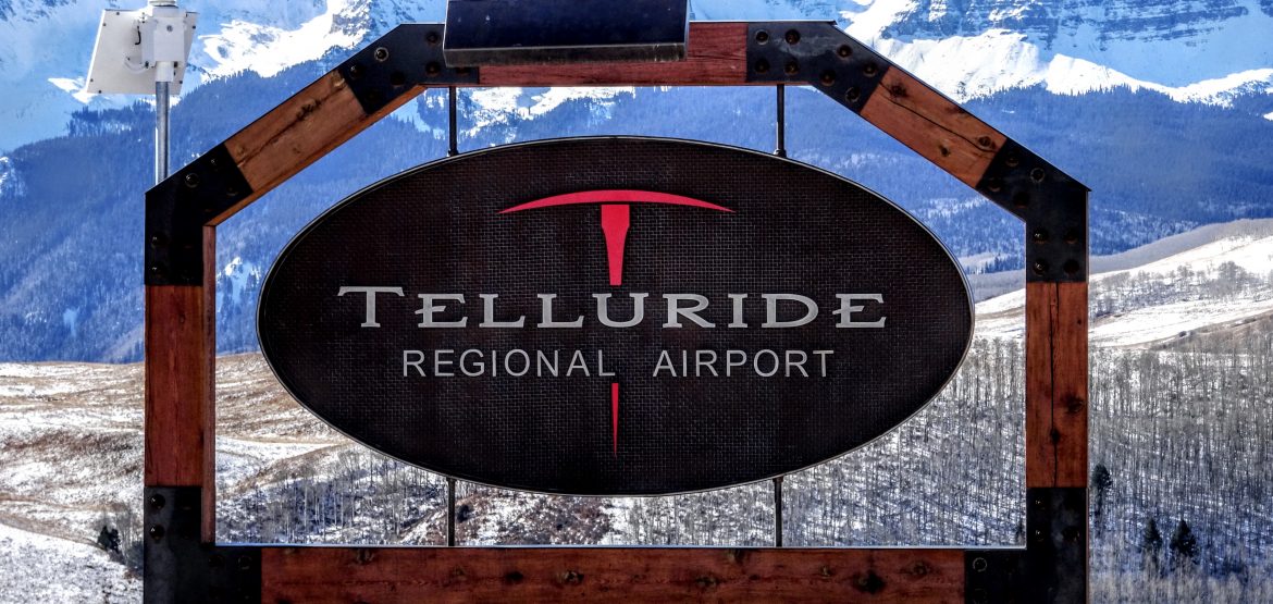 Telluride Regional Aiport Sign with mountains and a field behind.