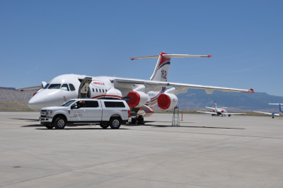 A jet parked on the runway with covers over the front of each engine and a truck parked near the door at Grand Junction Regional Airport