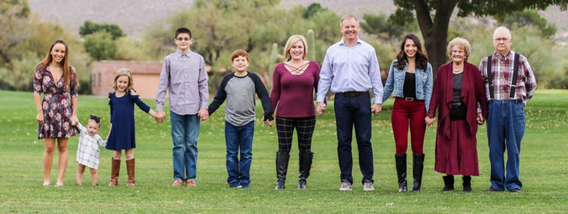 Keller Williams Southern Arizona. A group of adults and children stand in a line holding hands for a photo.
