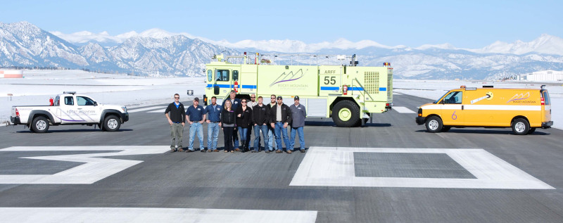 Rocky Mountain Metropolitan Airport operations staff in a group on the runway with vehicles position behind in the middle and on the left and right.