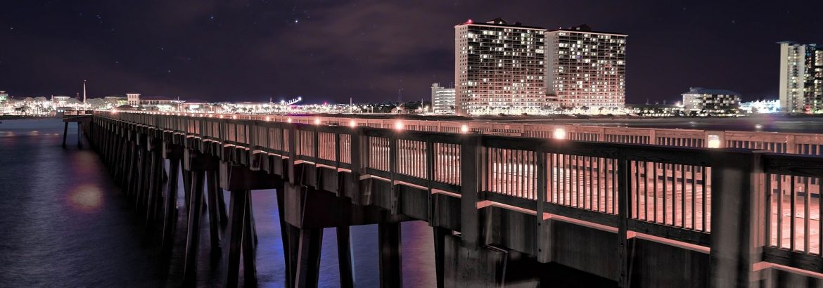 Bay County Florida. A pier at night with building across the water in the background.