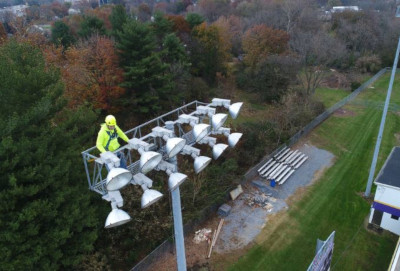 Reese Tower Services Inc. A worker standing at the top of a pole with stadium lights.