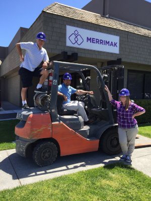 Merrimak Capital Company LLC Mak and the resale team outside by a forklift.