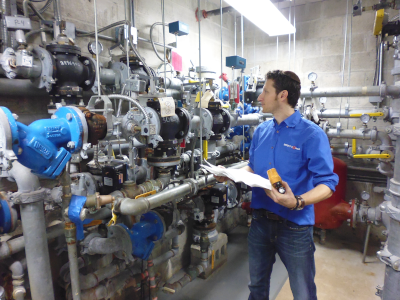 Bright Power employee Dave in a boiler room with a lot of pipes!