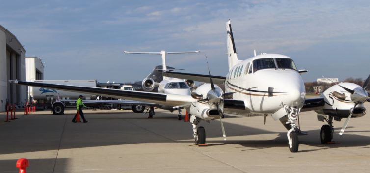 Chicago Executive Airport, planes sit in front of hangars with vehicles and workers around.