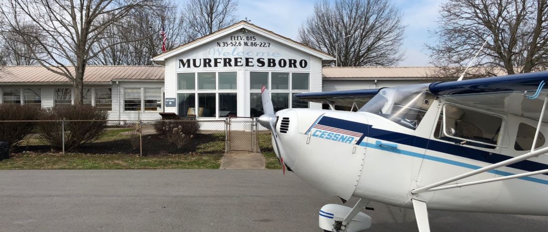 Murfreesboro Municipal Airport. Building with a Murfreesboro sign and a plane in front of it on the pavement.