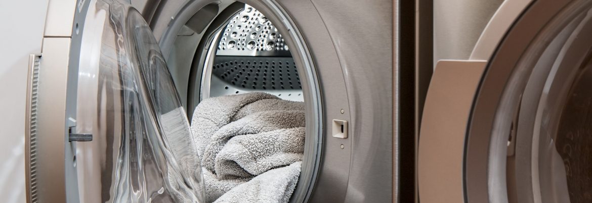 A washing machine with the door open and towels visible, with a dryer next to it.