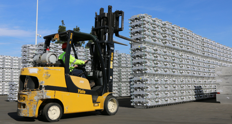 MHX Solutions forklift and metal ingots stacked.