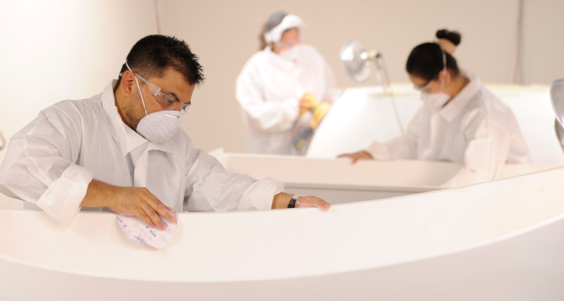 Clarke Products Inc. employees sanding bathtubs.