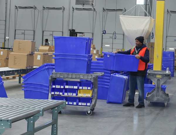 Future Forwarding Company warehouse employee moving blue totes.