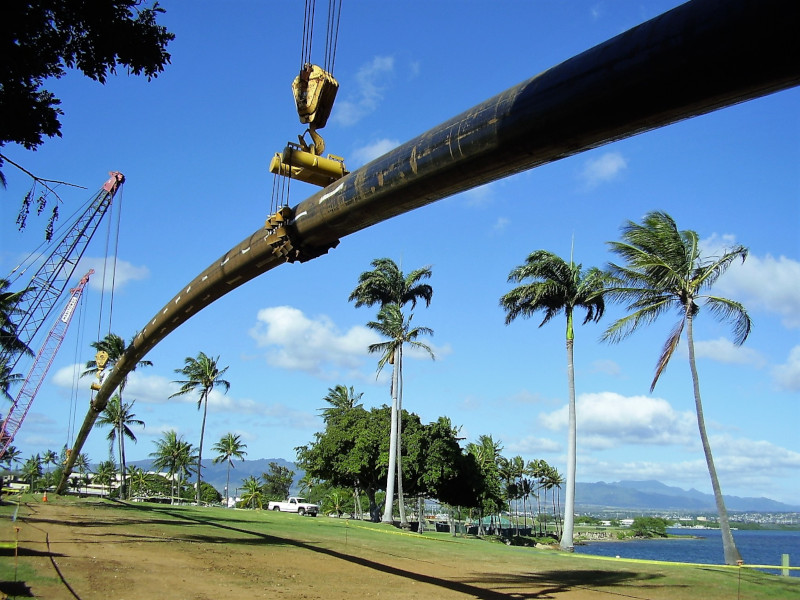 Laney Directional Drilling piping suspended in the air with blue skies and palm trees nearby.