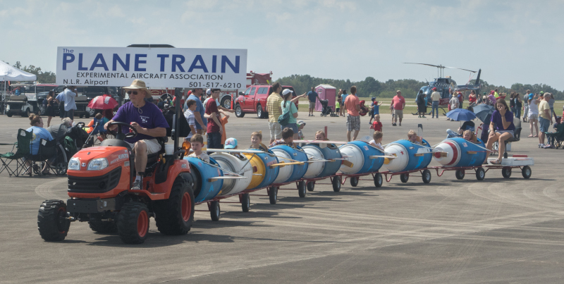 The North Little Rock Municipal Airport Plane Train with kids riding behind a tractor in cars that look like airplanes.