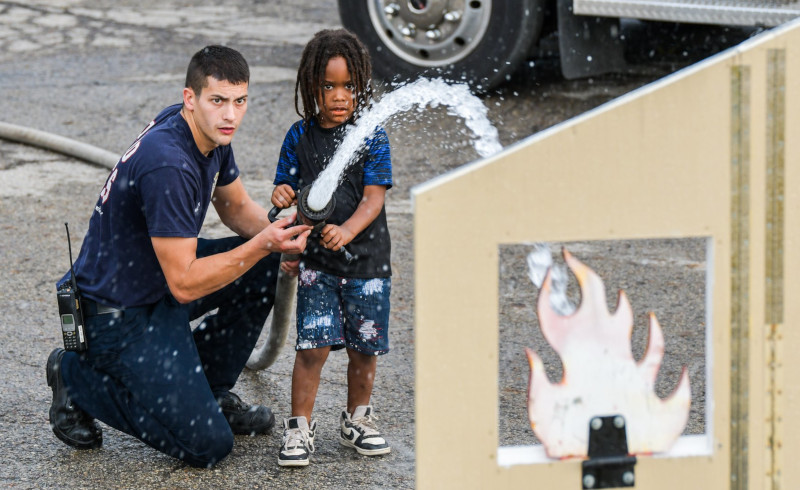 Reynoldsburg, Ohio Firefighter using a fire hose with a child to hit a target.