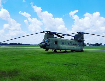 Tuscaloosa Regional Airport, military helicopter in the grass. Blue sky and puffy white clouds behind.