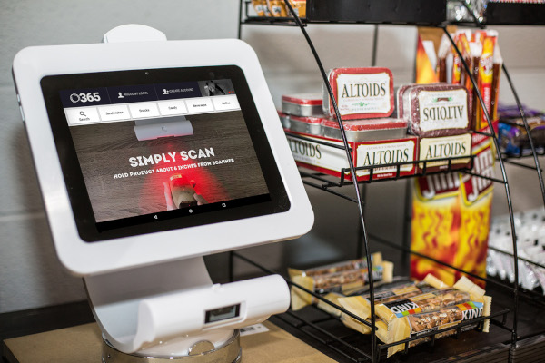 365 Retail Markets nanomarket hardware. An item scanning device sits on a small counter top with a rack of snack items next to it.