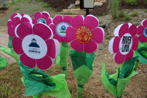 Asheville, North Carolina paper flowers on grass. One has the city name and another says River Link.