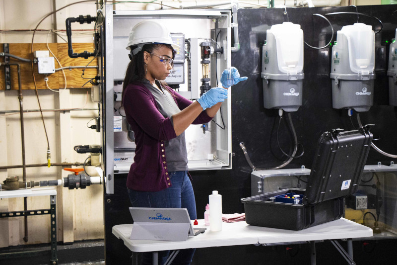 Chem-Aqua employee testing something in a tube wearing protective gear.