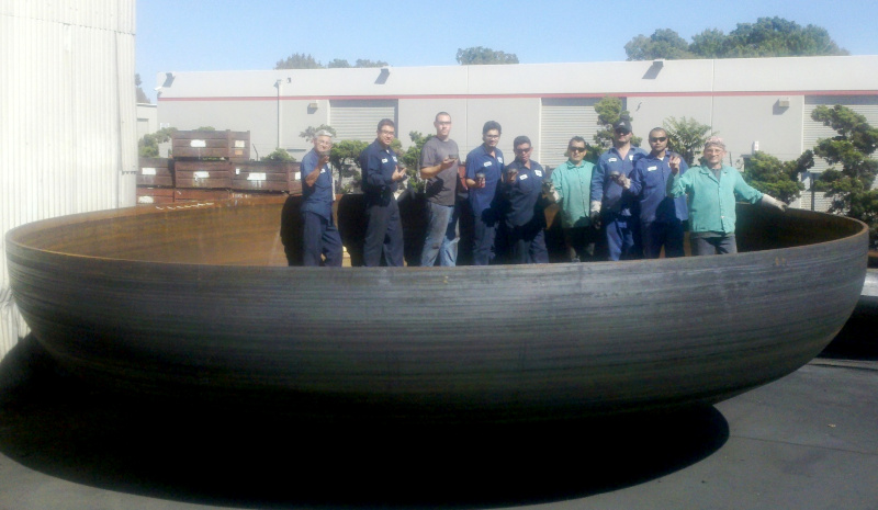 Commercial Metal Forming employees posing for a photo while standing inside of a large round metal object, nine people with room to spare!