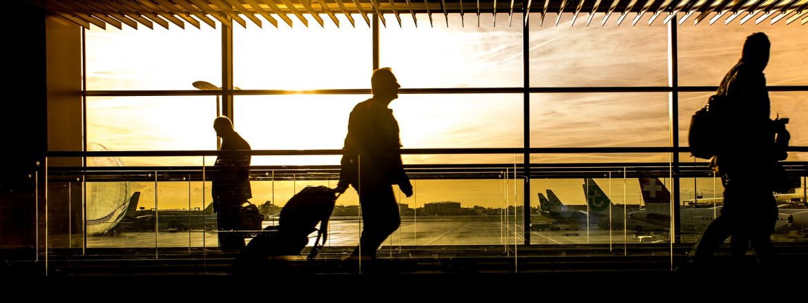 Bright sun behind silhouettes of people walking in an airport.
