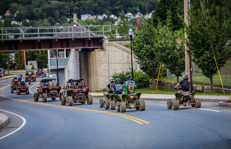 Berlin, New Hampshire city street with a line of ATVs travelling on the road.