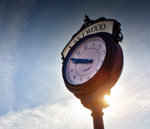 Lakewood Township, New Jersey clock on a pole with the sun glinting partially behind.