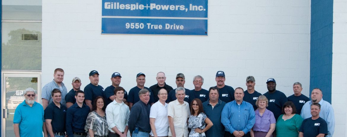 Gillespie and Powers group photo of employees in front of their sign.