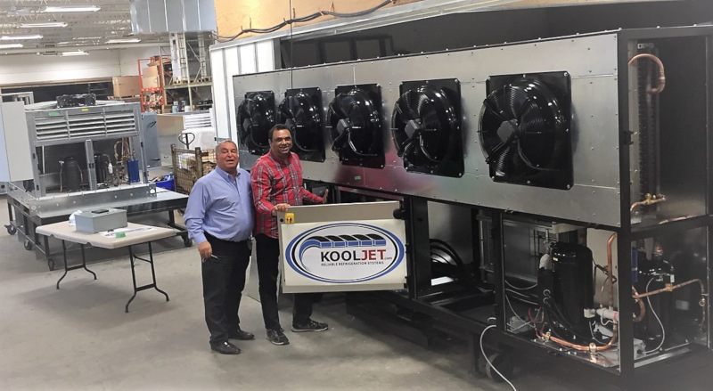 KoolJet employees posing next to a unit with a panel open showing the KoolJet logo.