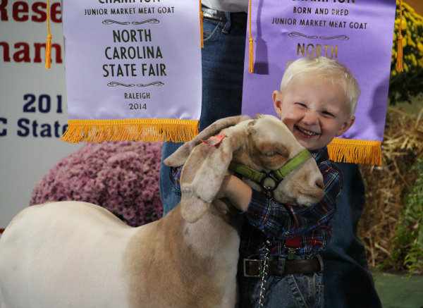 North Carolina State Fair, a boy smiles hugging an animal.