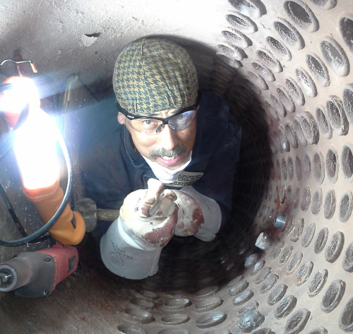 California Boiler employee crawling inside of a tight space while working.