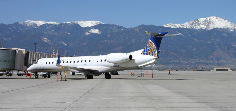 The Colorado Springs Airport, a commercial jet at the terminal building with mountains behind.