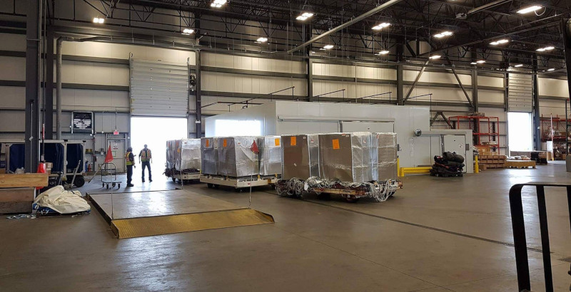 Flying Fresh Air Freight interior of a warehouse with workers and freight on pallets.