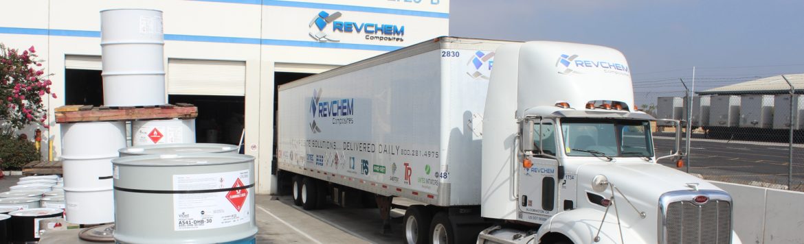 Revchem Composites Inc building with a semi truck out front and metal barrels.