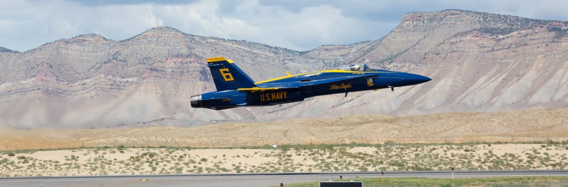 Grand Junction Regional Airport with a Blue Angel jet flying over the runway.
